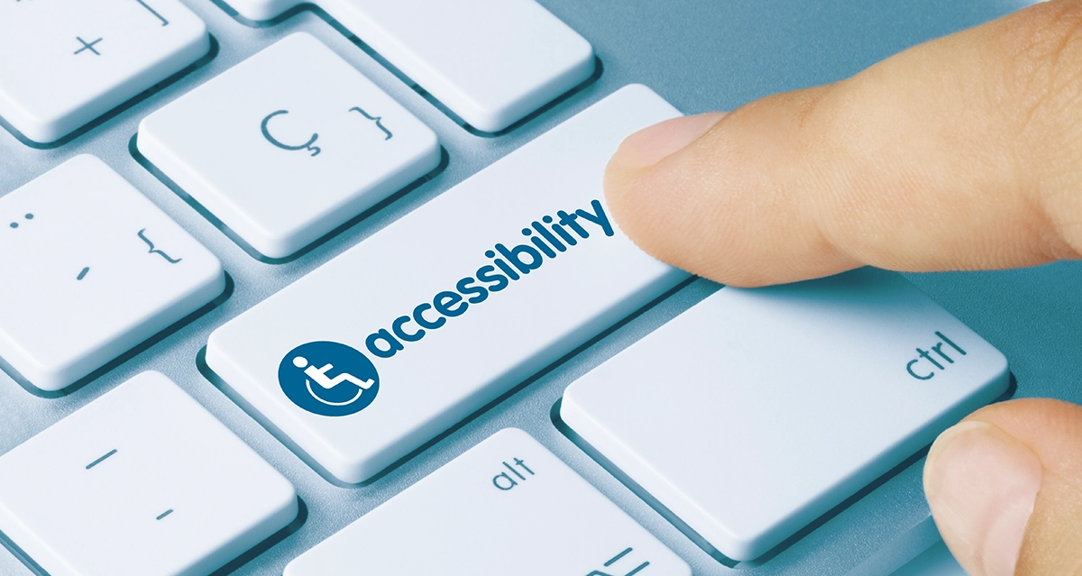 Close up of a computer keyboard with someone pressing a key labeled "accessibility".