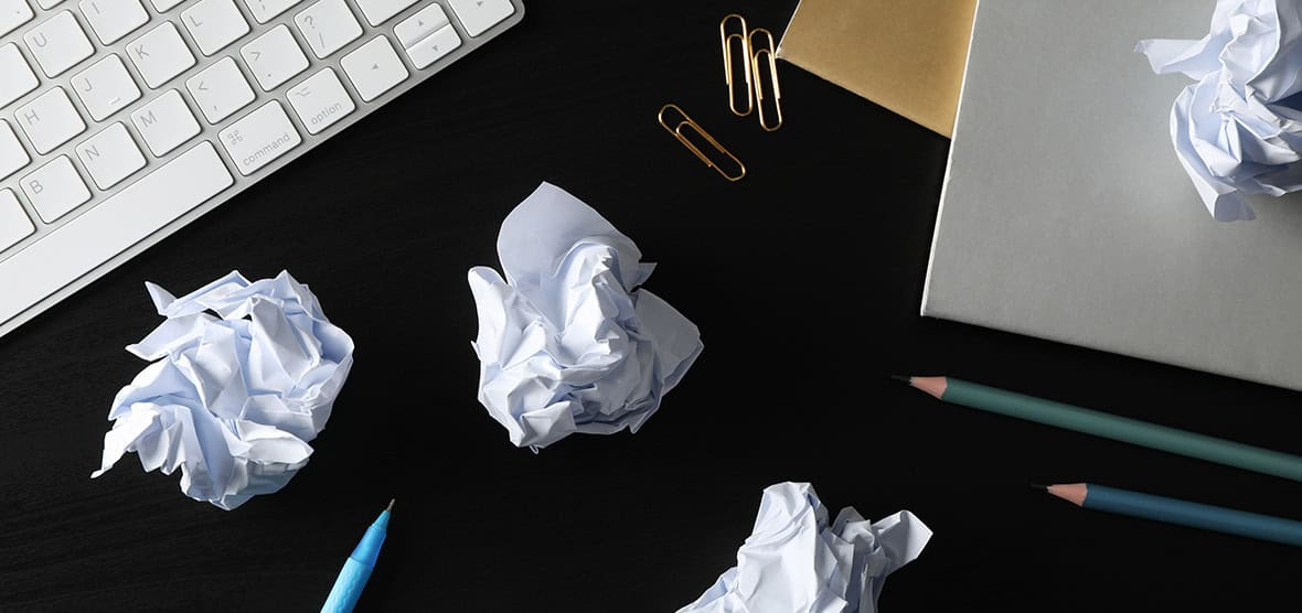 Crumpled up pieces of paper on a business persons desk