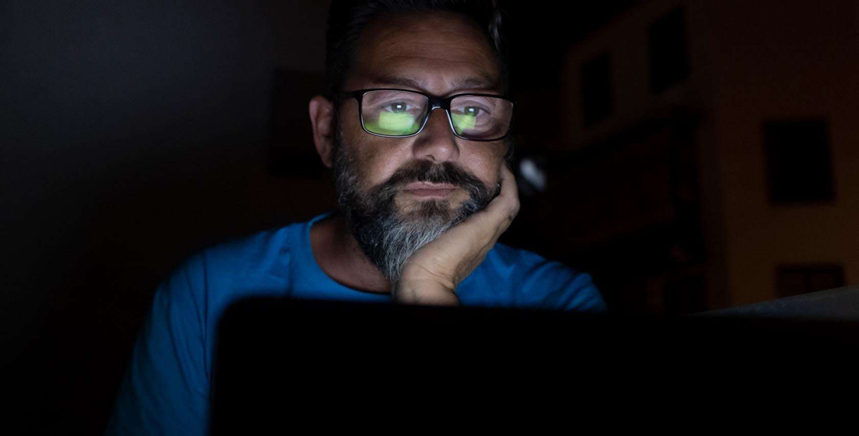 man staring at computer in the dark