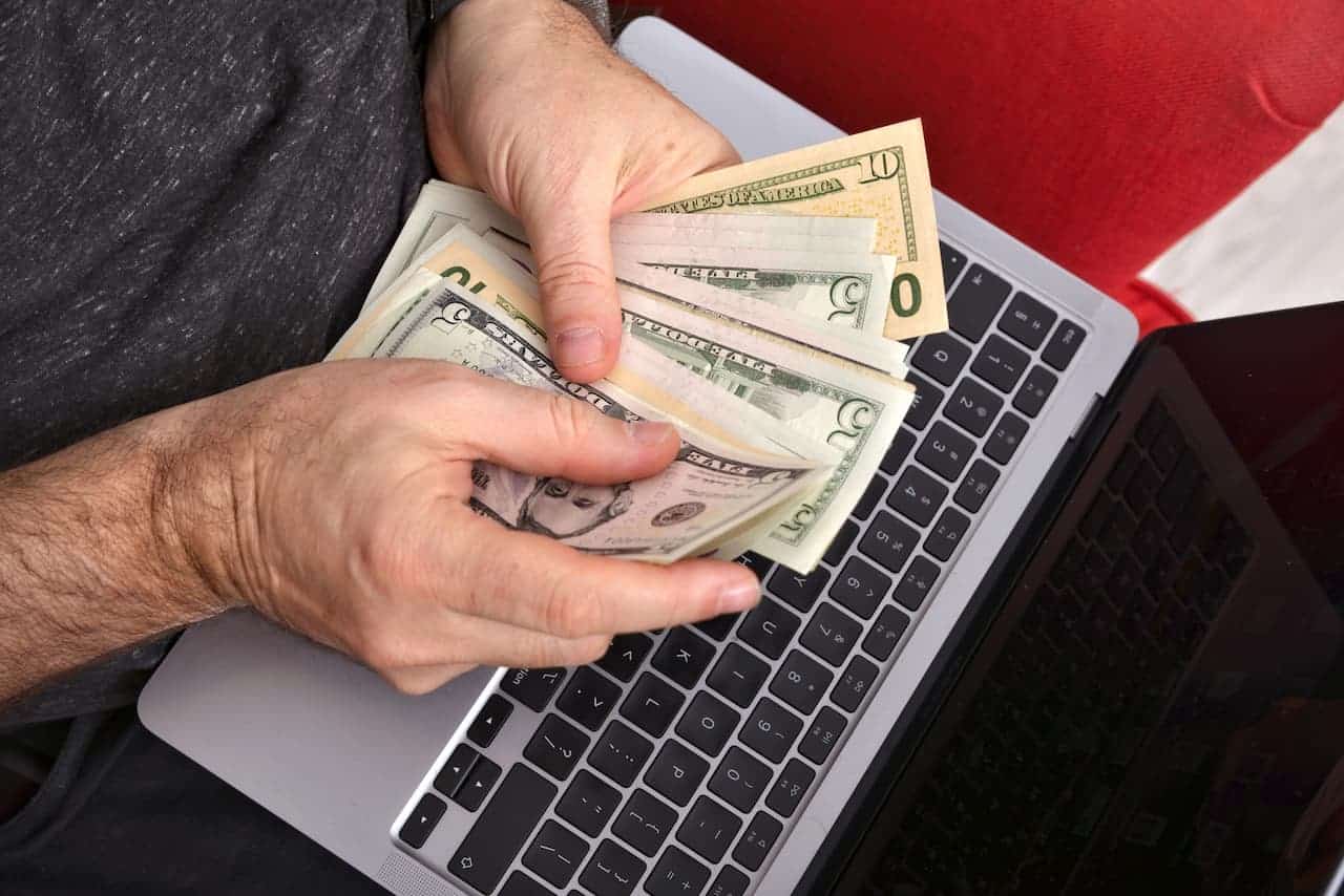 Hands counting cash over laptop keyboard