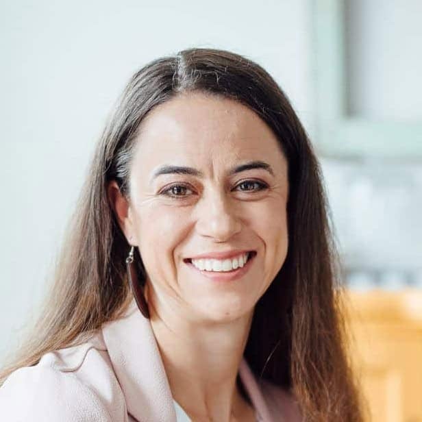 Smiling woman with long brown hair in a bright room